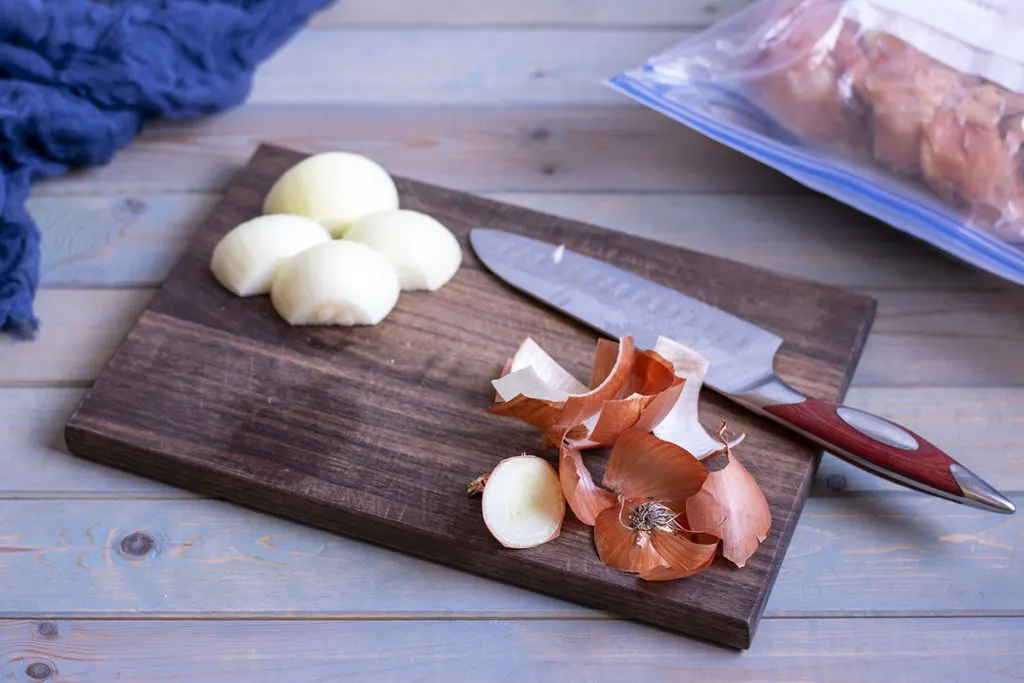 Onions sliced on a cutting board with a knife laying next to them. 