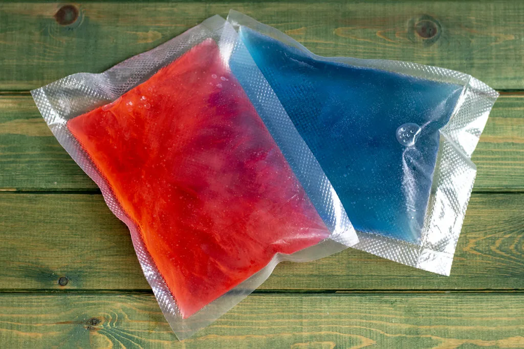 Homemade freezer ice packs, one in red and one in blue.