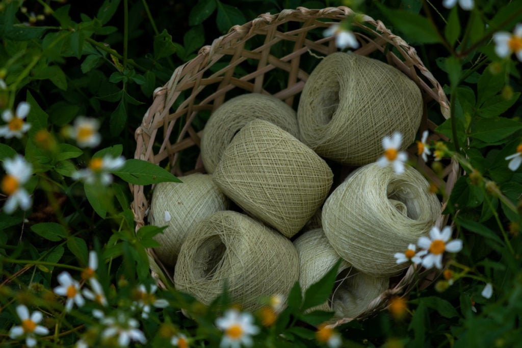 Cakes of pale green yarn surrounded by flowers.