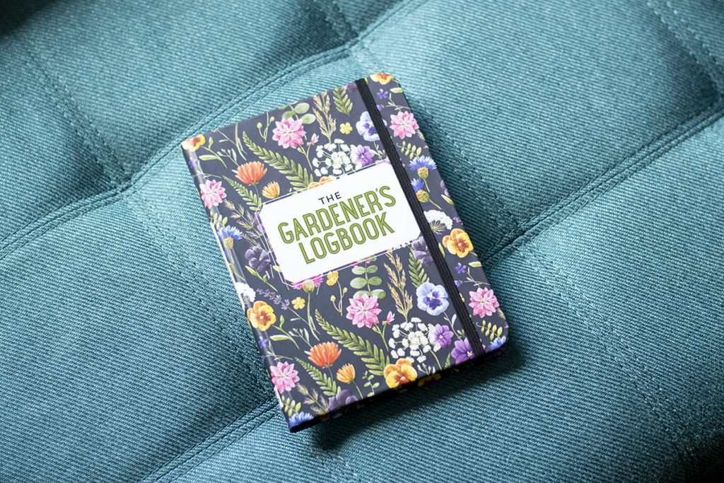 A photo of the book, "The Gardener's Logbook" on a cushioned bench seat. 