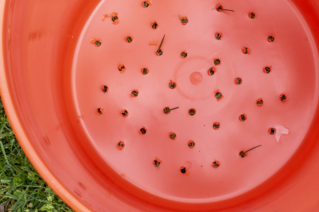 Bottom of bucket with holes drilled in it and burs on the outside of the holes.