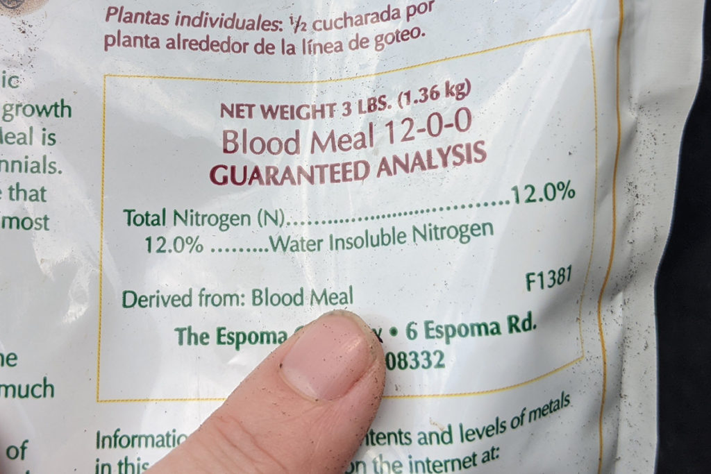 Finger pointing at the bag of the bag of fertilize showing the nutrient analysis.
