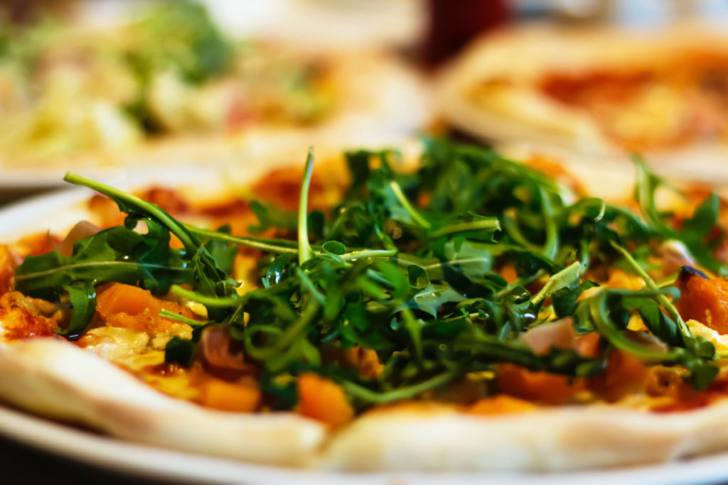 Close up of a pizza topped with fresh arugula. 
