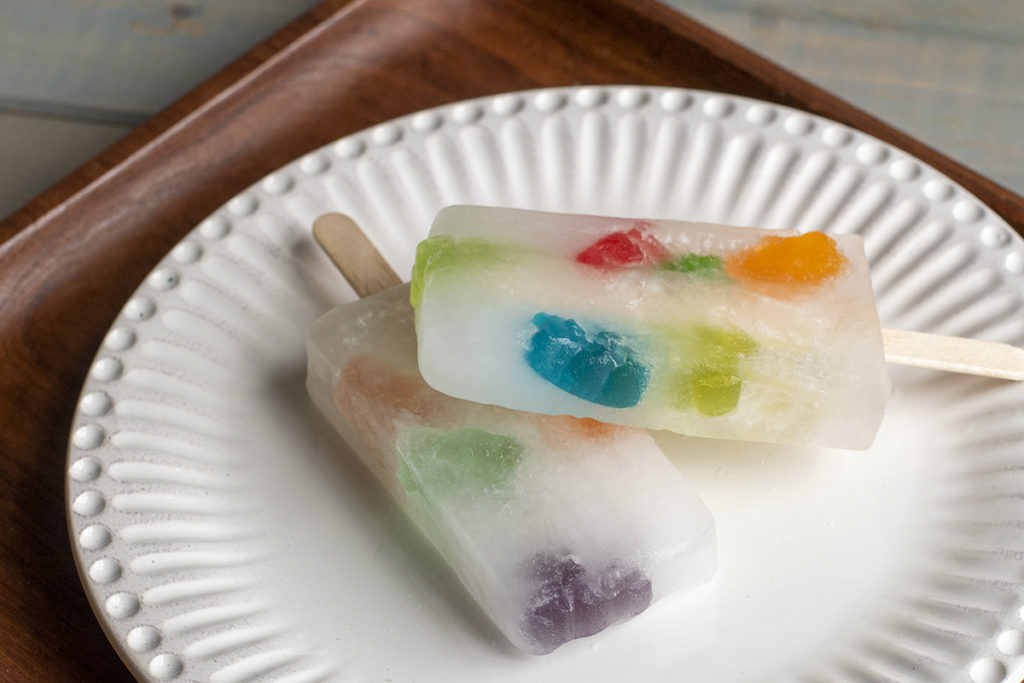 Popsicles made of sprite with brightly colored gummi bears frozen inside them.