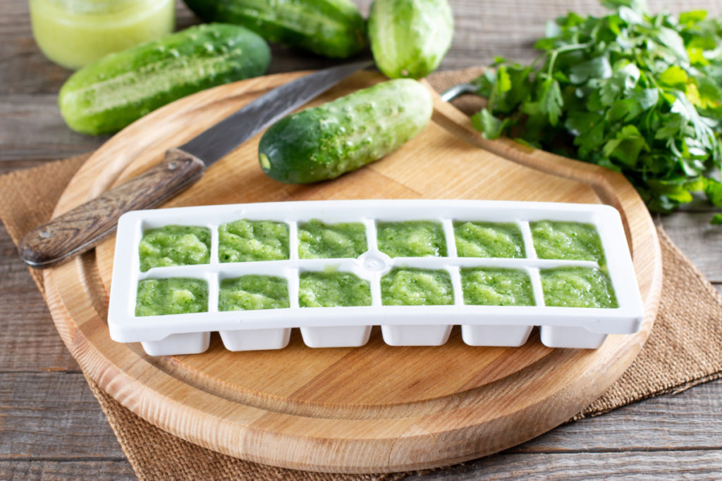 An ice cube tray filled with pureed cucumber