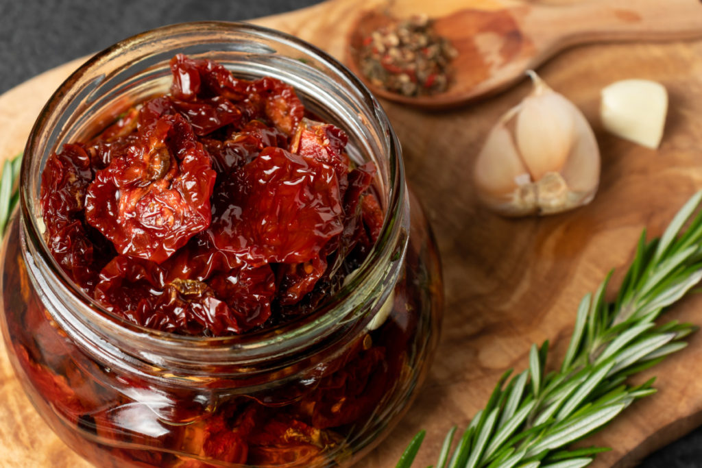A small jar filled with sun dried tomatoes and oil