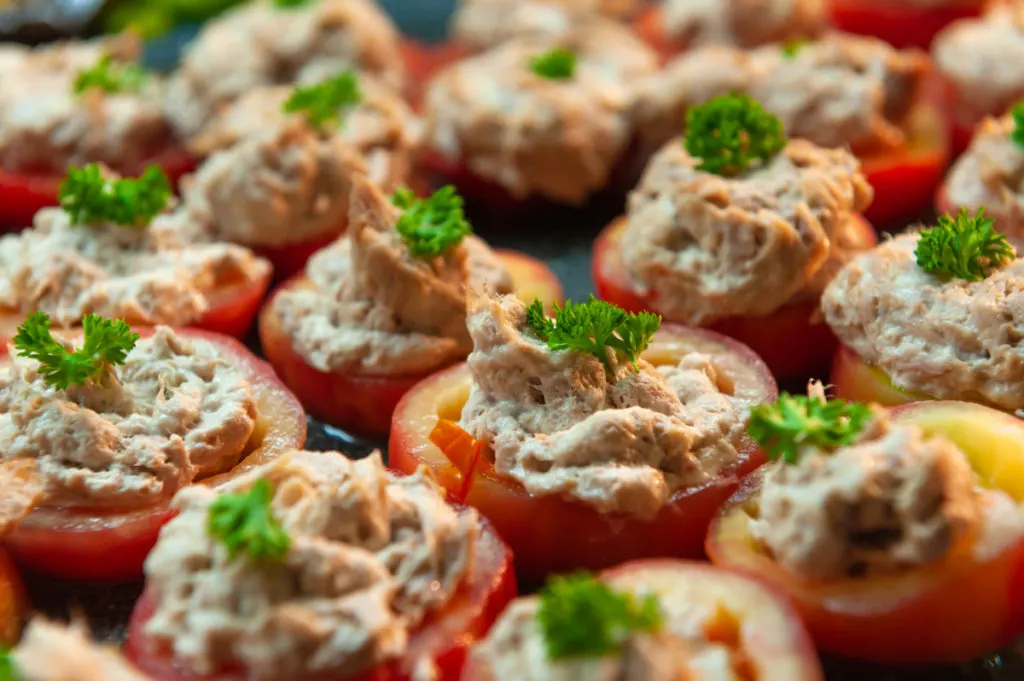 Overhead view of tomatoes stuffed with tuna salad and garnished with parsley sprigs