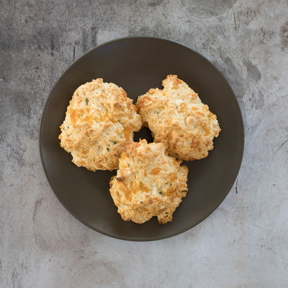 Overhead view of cheddar chive biscuits in a brown bowl.