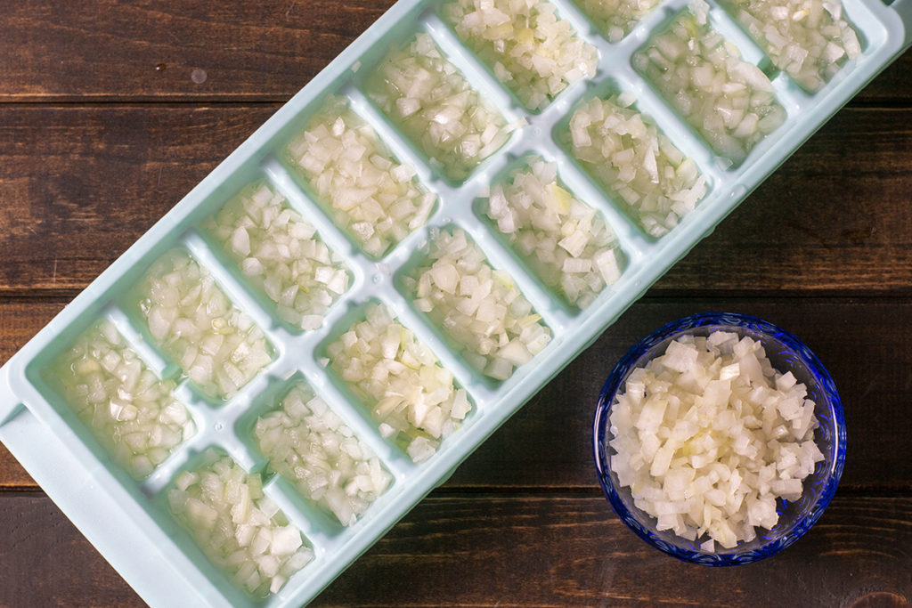 An ice cube tray has been filled with finely minced onion.
