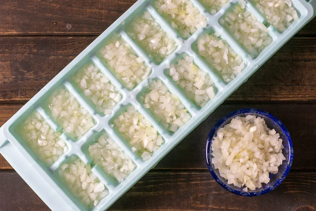 An ice cube tray has been filled with finely minced onion.