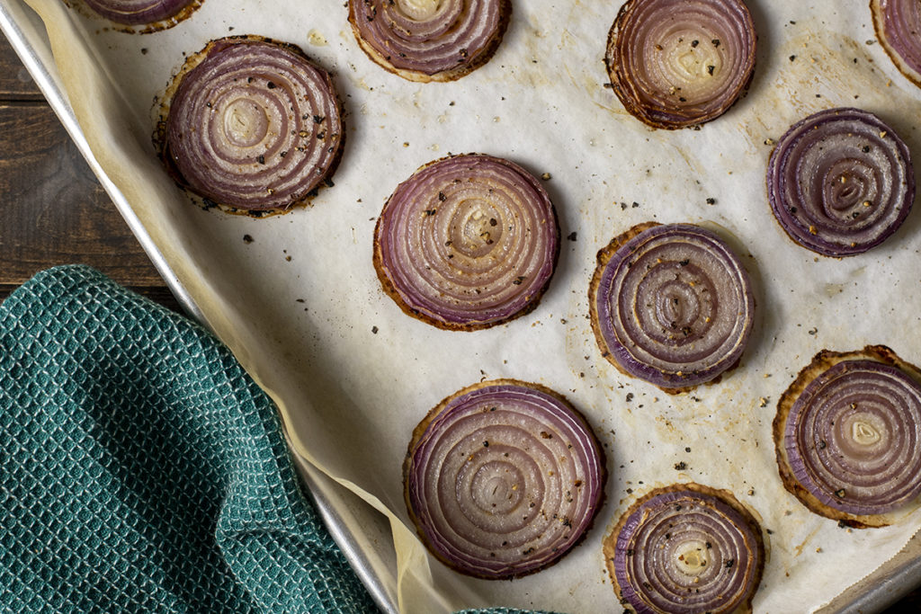 Roasted red onions on a parchment lined baking sheet. 