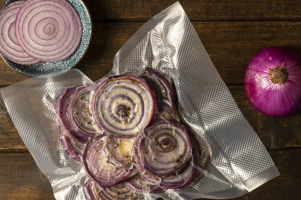 A vacuum sealed bag with frozen roasted red onions.