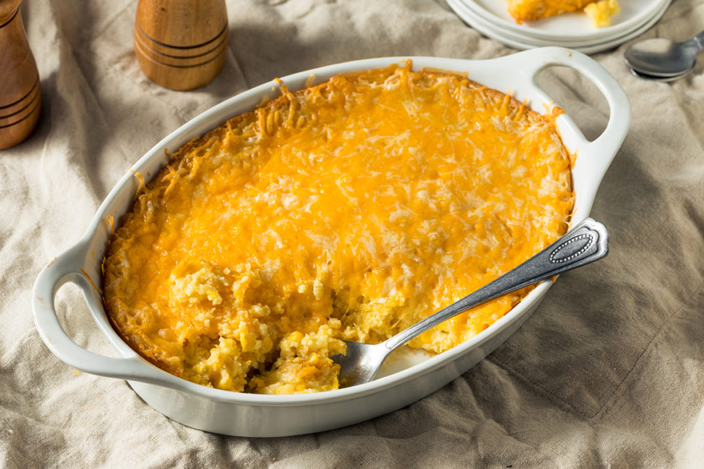 A sweet corn casserole with a helping missing from the dish