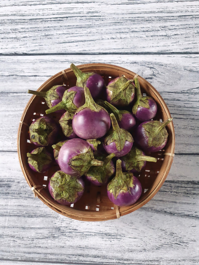 A basket of tiny lavender colored eggplants. 
