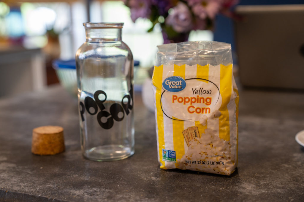 bag of popping corn next to an empty jar labeled popcorn.
