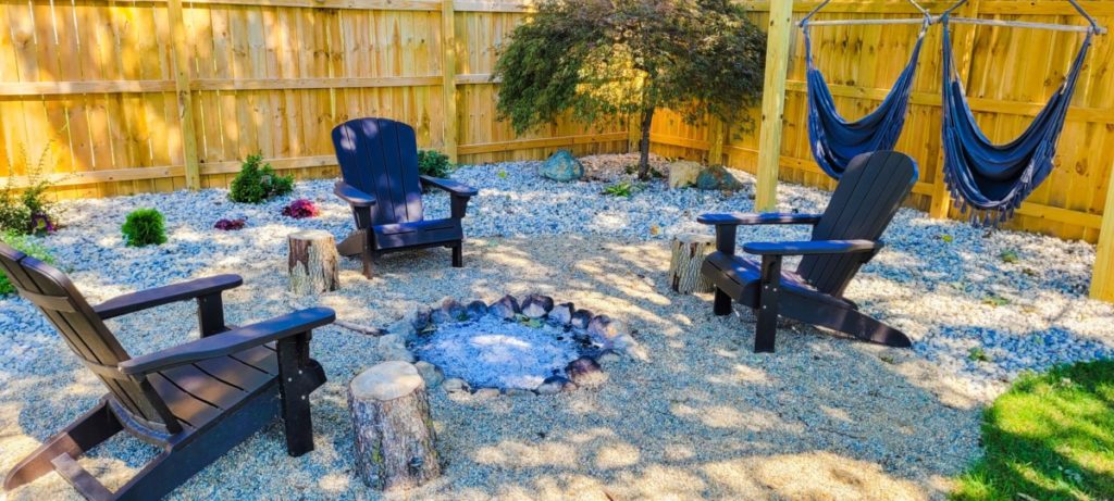 A boho inspired backyard fire pit with blue chairs and blue hammock swings.