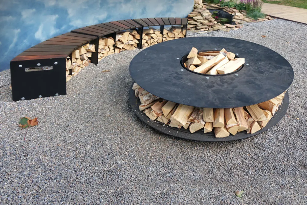 A circular steel fire pit with a ring of plate steel for grilling. 