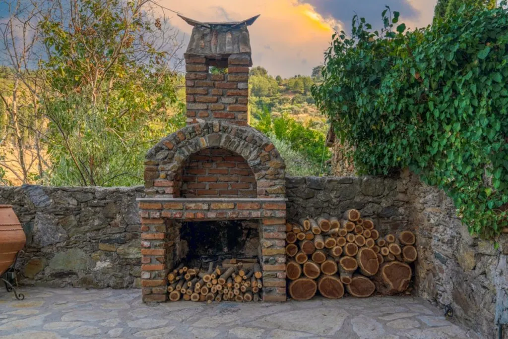A brick fireplace built into a backyard. 
