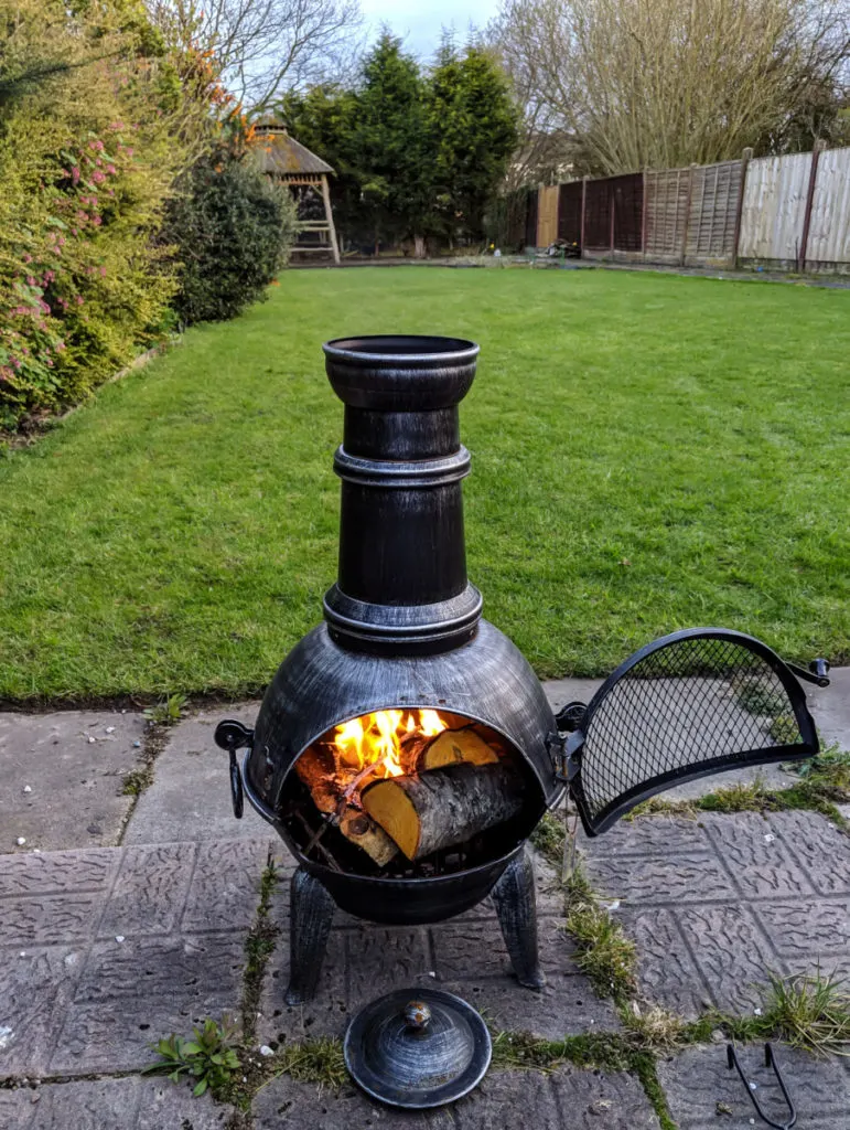 A metal chiminea with a fire in it.