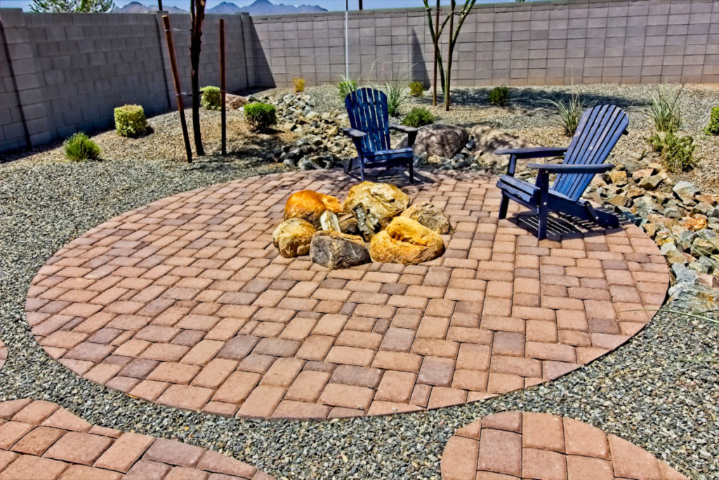 A round patio with a fire pit made of boulders.