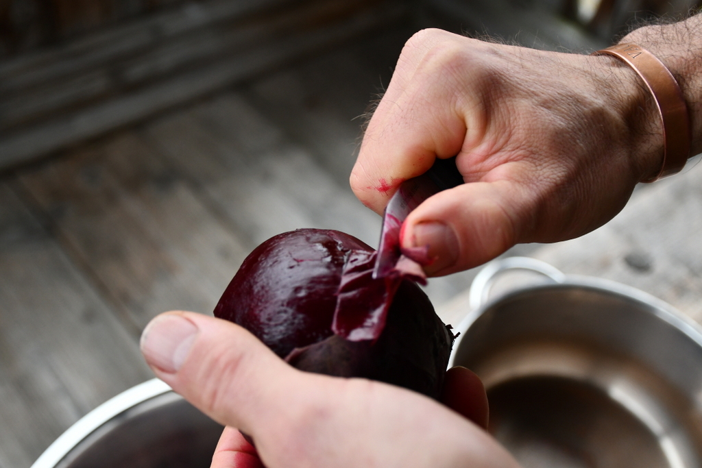 Man's hands peeling a roasted beet
