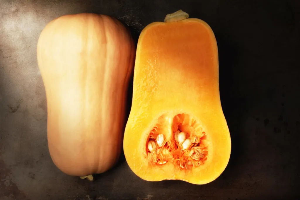 A butternut squash cut in half with the seeds still inside