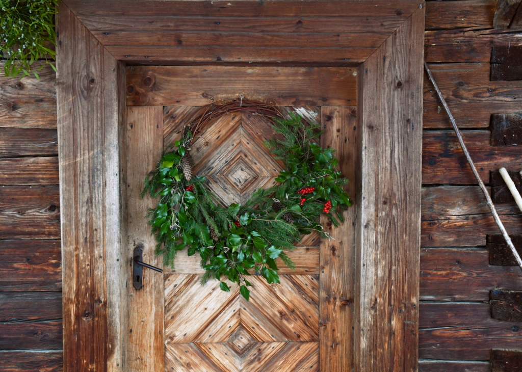 grapevine wreath adorned with greenery and berries hanging on door