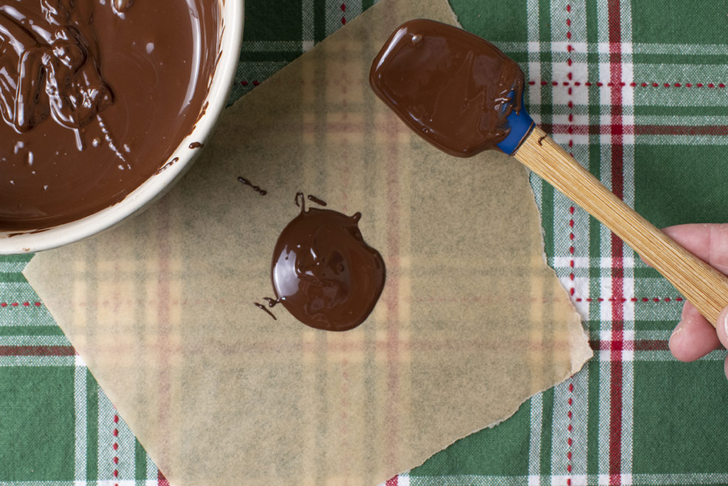 A spoonful of chocolate dropped onto parchment paper