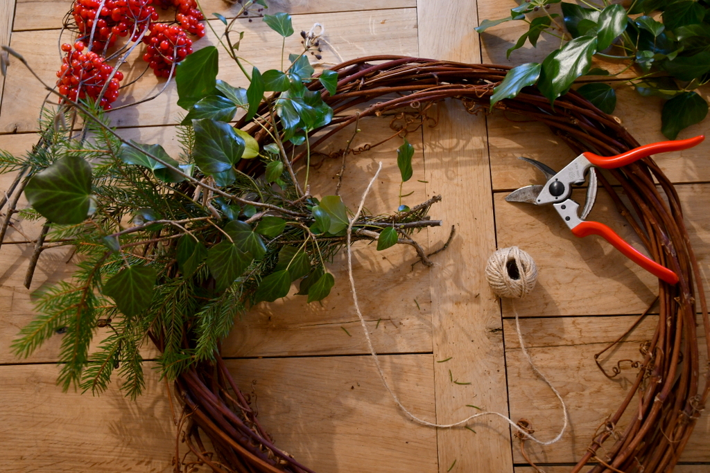 Bundle of greens held together with twine set on the top of empty wreath