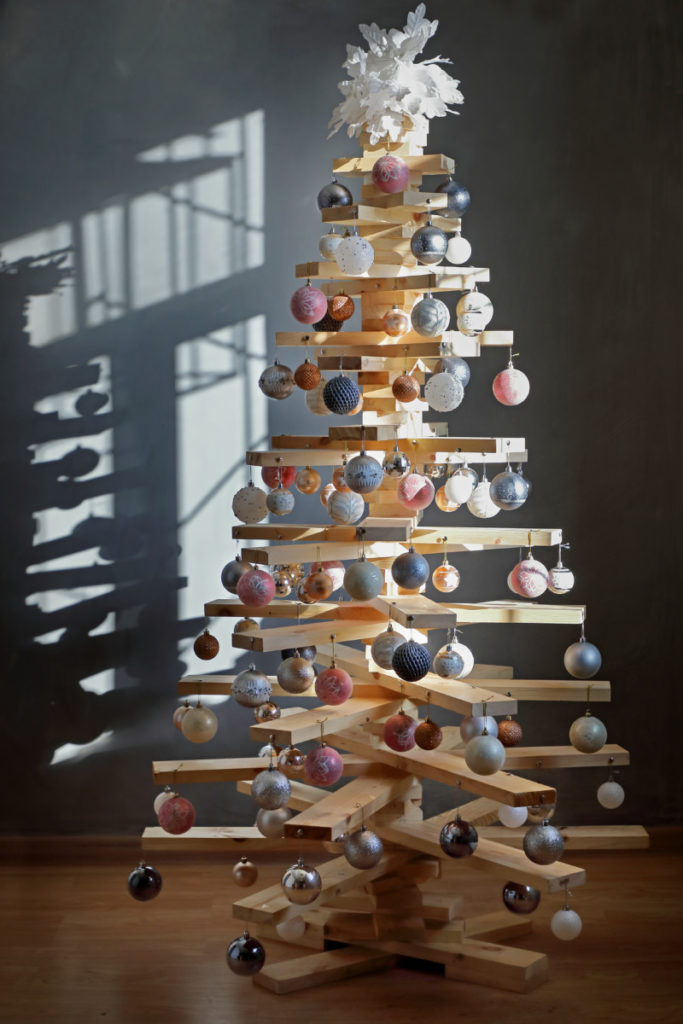 Scrap lumber Christmas tree covered in Christmas ornaments