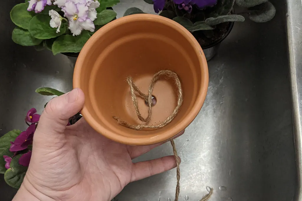Small terracotta pot with braided twine threaded through the drainage hole.
