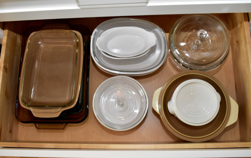 A drawer with around a dozen casserole and baking dishes inside it.

