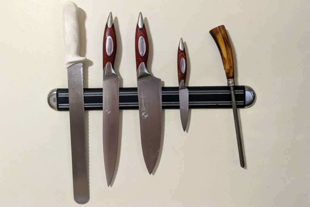 Author's four knives and honing wand on a magnetic knife holder.