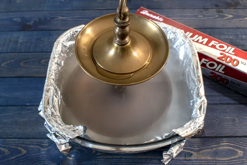 Brass serving tray being dipped into boiling water with aluminum and baking soda.