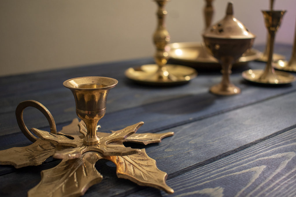 Brass candleholder in foreground with other brass candleholders in background. 
