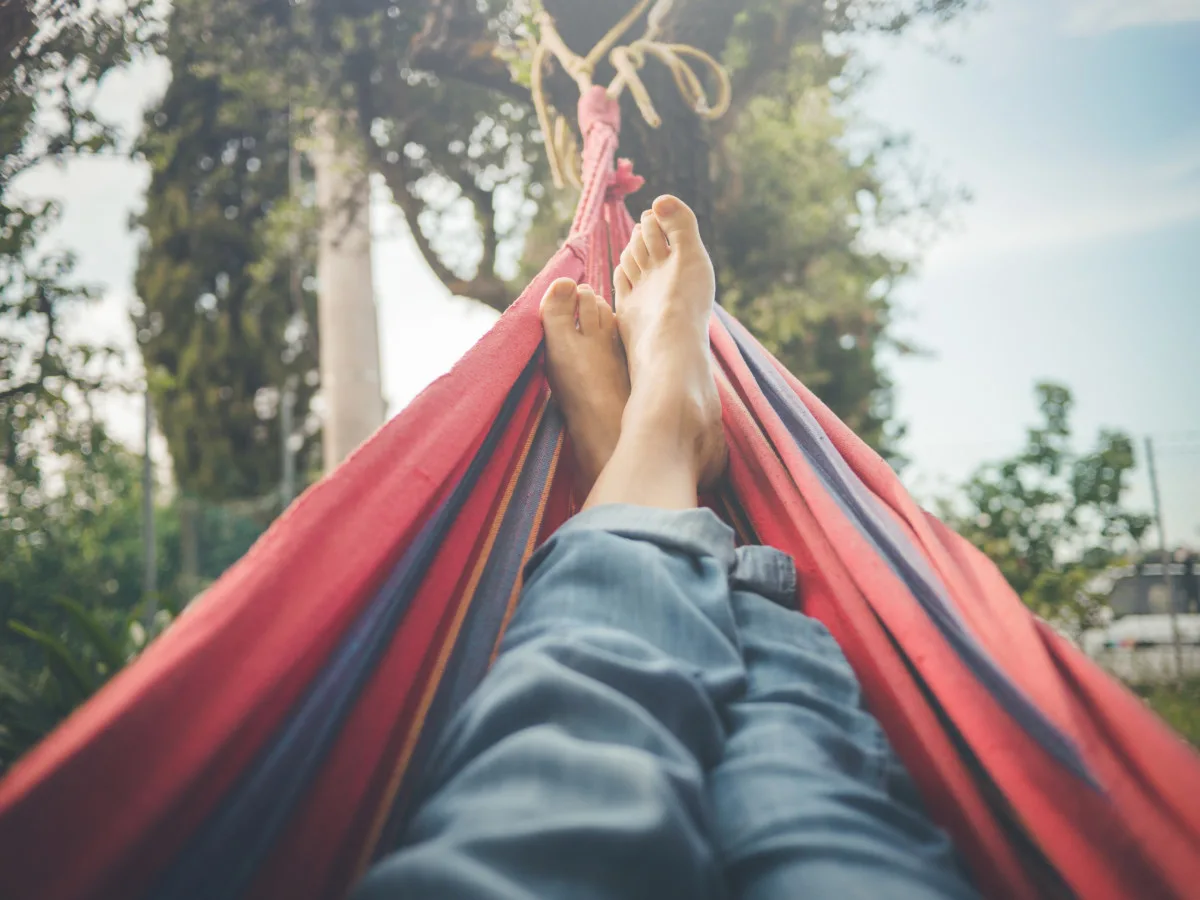 Someone's feet and legs lying in a hammock.