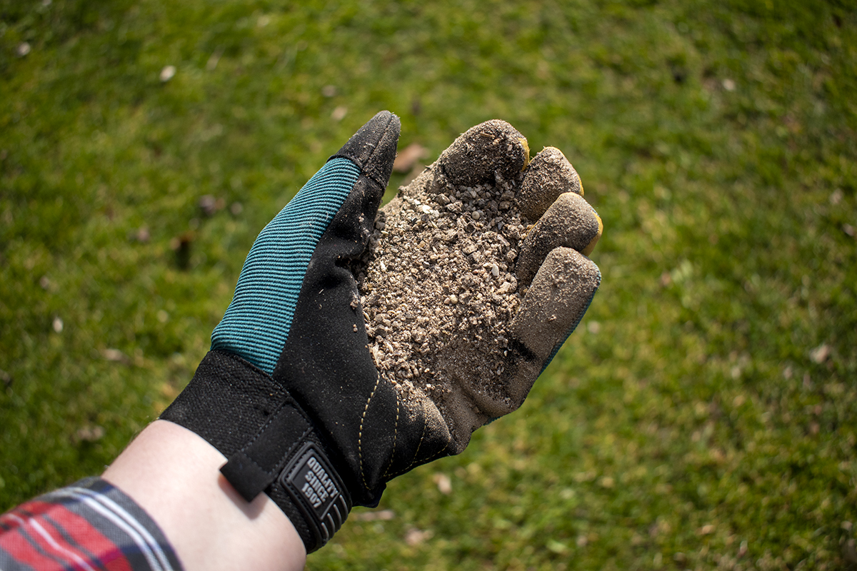 Hand with garden glove holding pelletted fertilizer