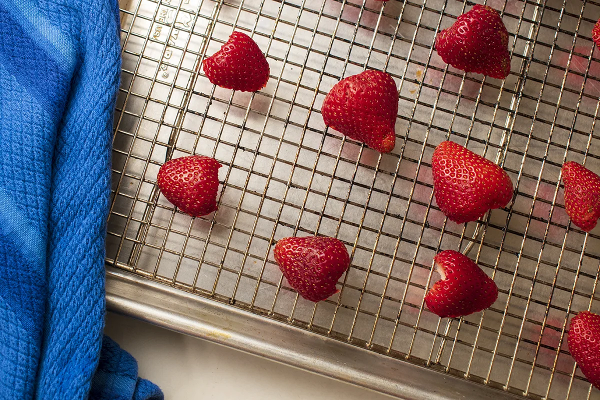 Halved strawberries on cooling rack on top of baking sheet