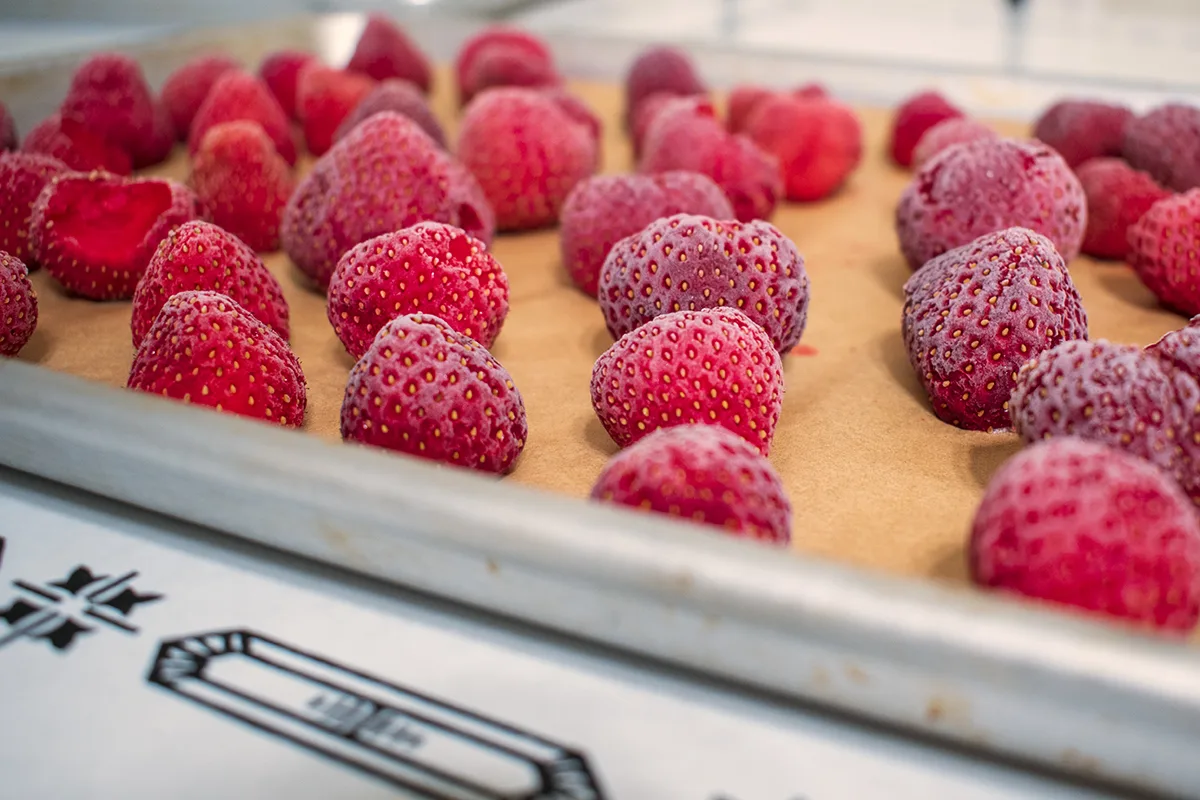 Whole frozen strawberries on parchment-lined baking sheet.