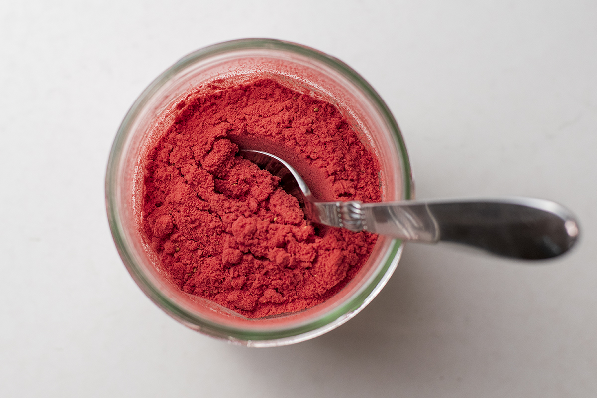 Close up of strawberry powder in a jar with a spoon
