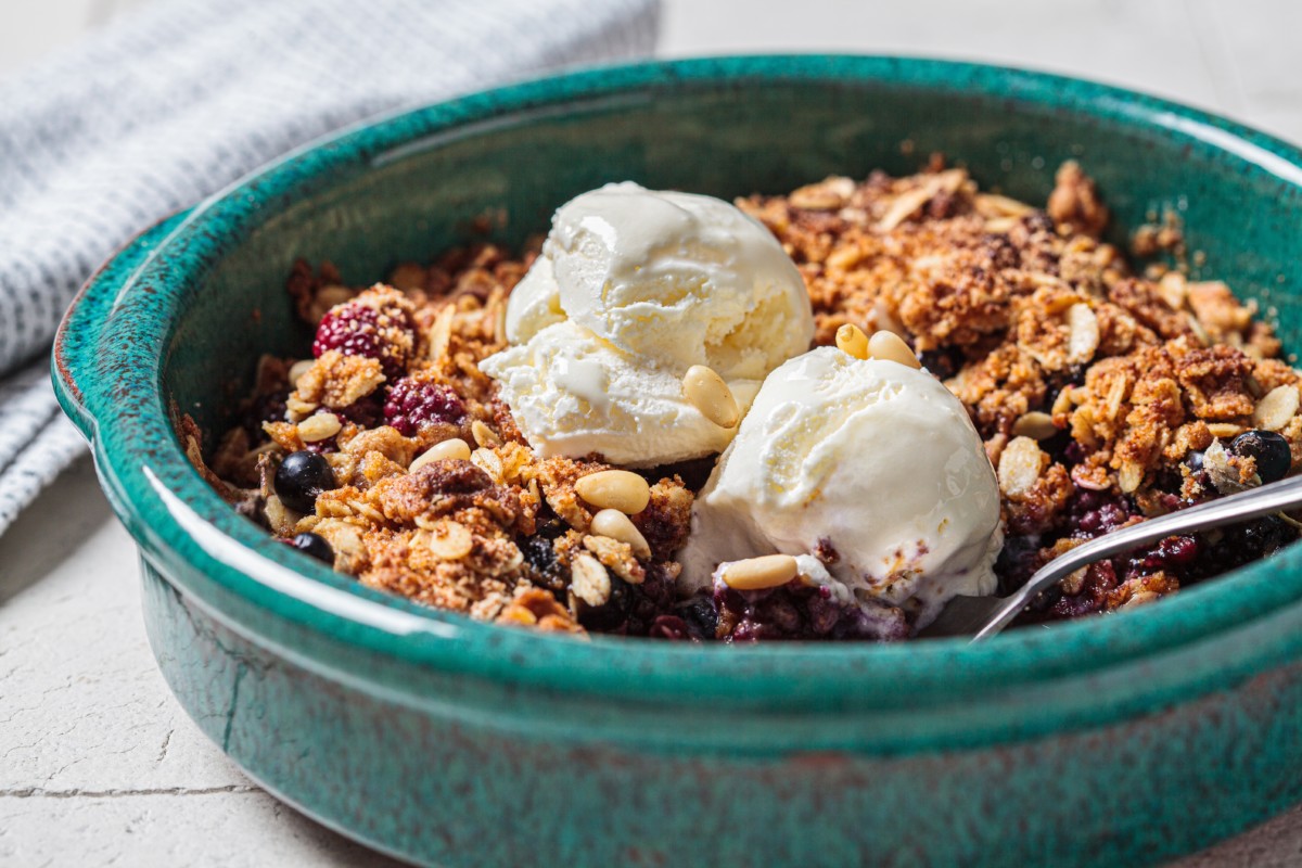 A dish of blueberry crisp topped with scoops of vanilla ice cream. 