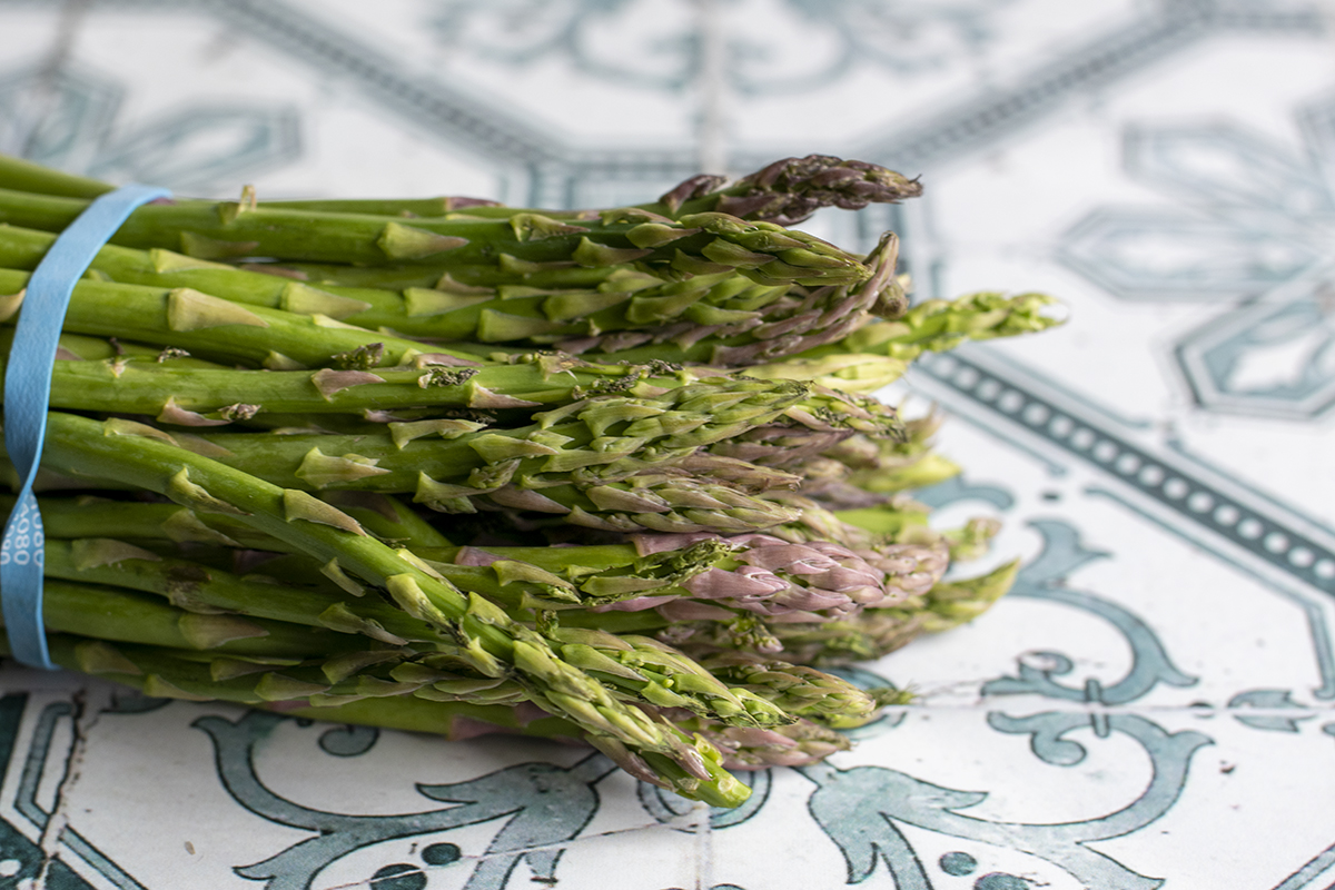 A bundle of asparagus stems, focus on the buds.