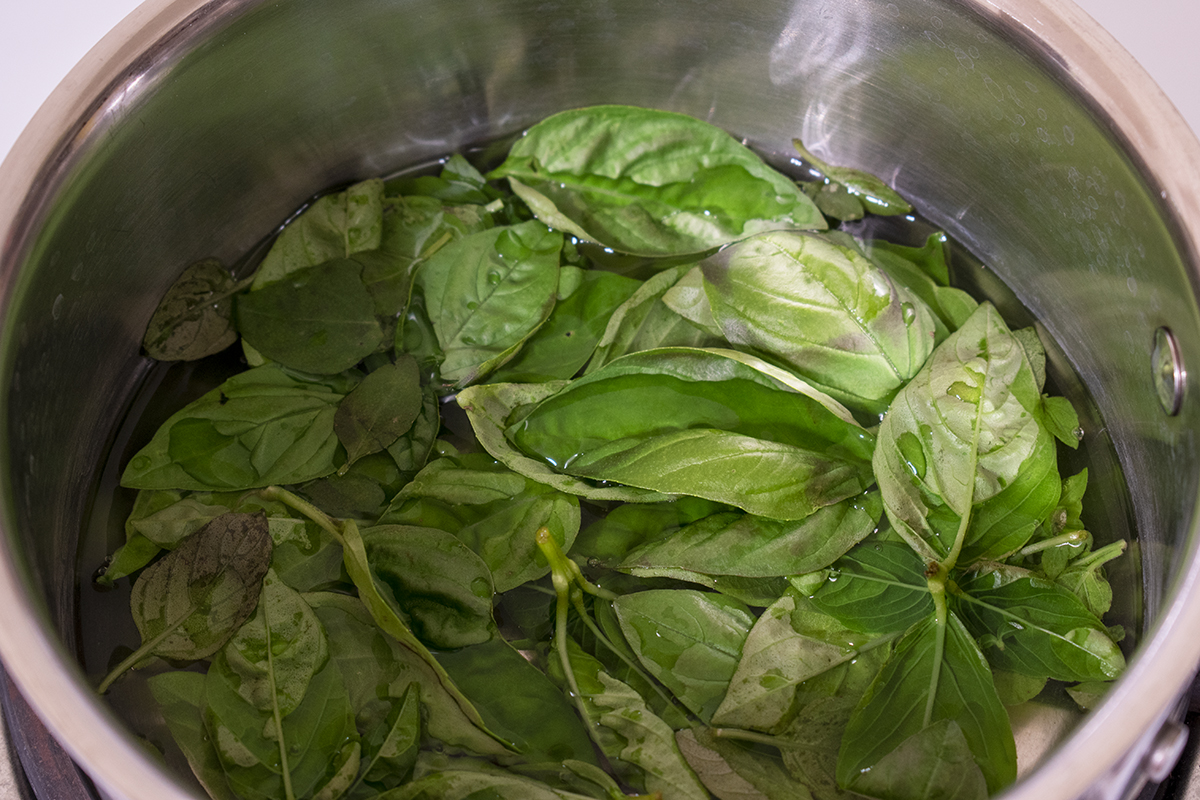Pan with fresh basil leaves and water in it.