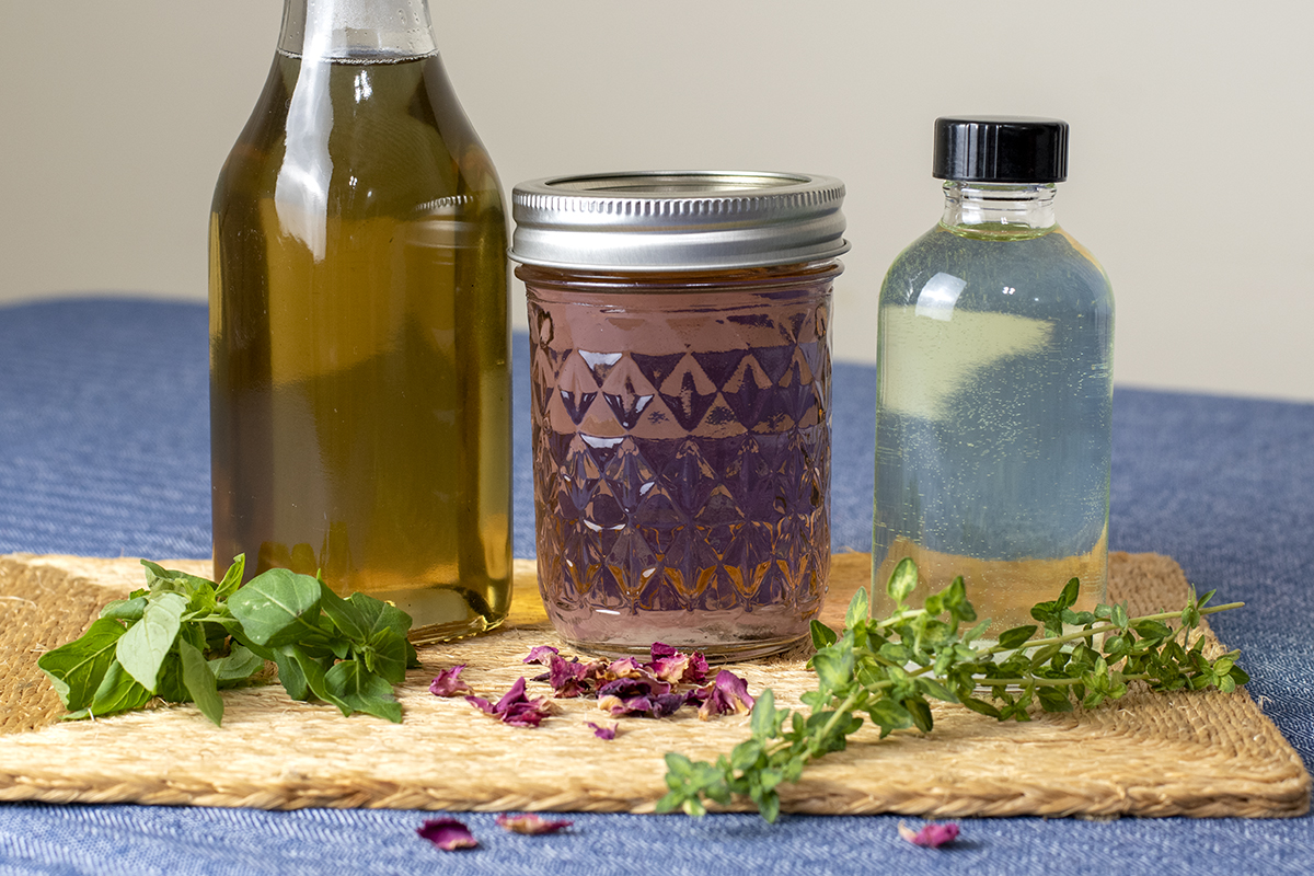 Several herbal syrups in jars on a straw trivet
