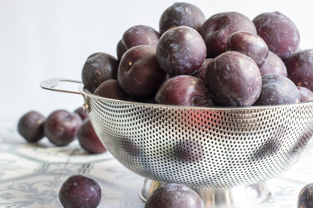 Large colander filled with plums