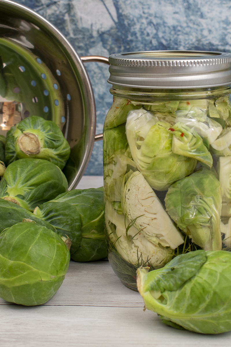 Brussels sprouts next to a jar of pickled sprouts