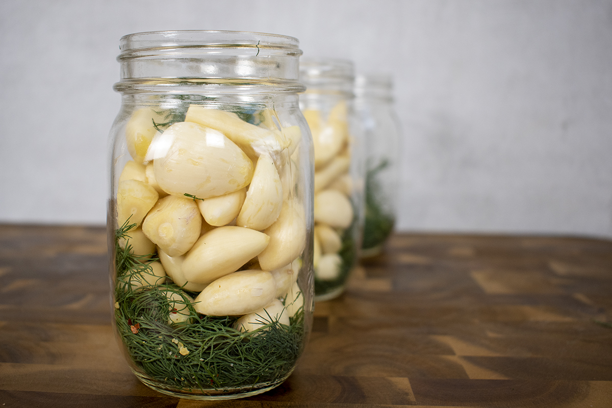 Mason jars filled with garlic, dill and pepper flakes