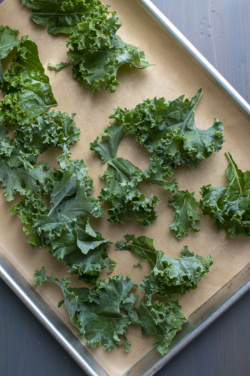 Torn kale leaves on baking sheet.