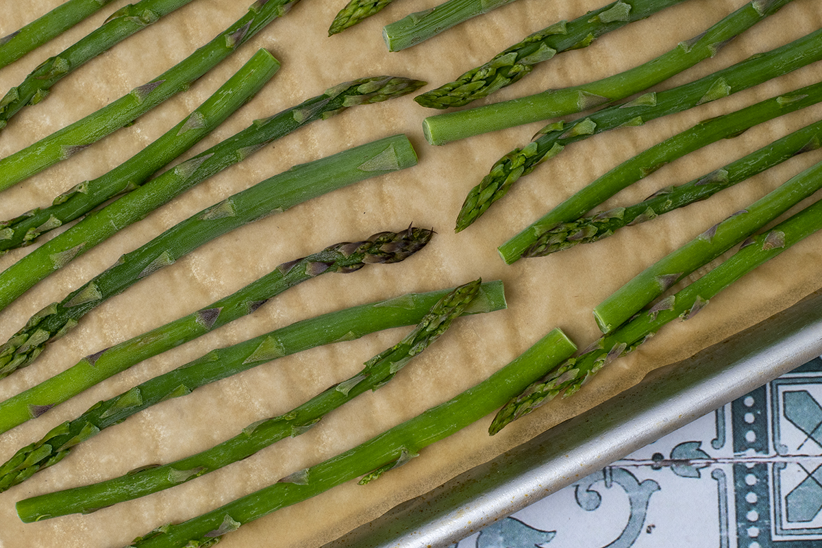 frozen asparagus stems on a parchment lined baking sheet