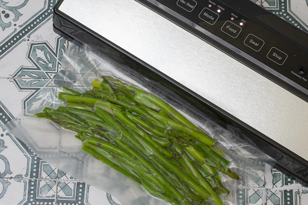 Vacuum sealer being used to seal a package of asparagus stems